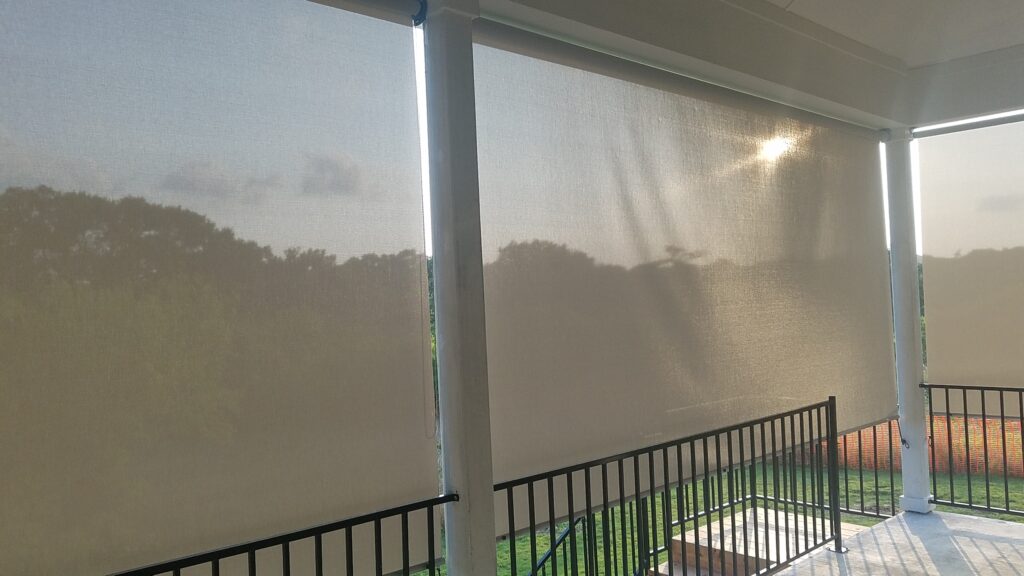 Retractable grey white patio roller shade.