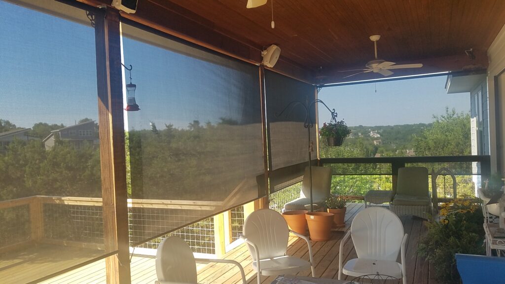 Exterior retractable roller shades installed on a covered wooden deck patio in Austin Texas with scenic hill country views