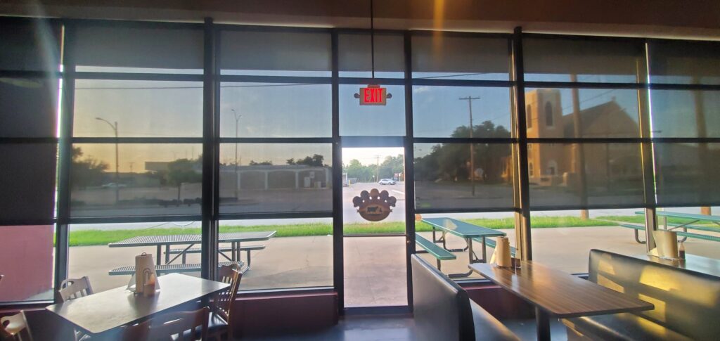 Interior commercial roller shades installed on large restaurant windows in Austin Texas providing sun control and glare reduction